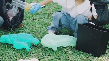 A child is sitting on the grass with a trash can and a plastic bag video