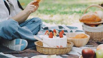 A woman is sitting on the grass with a cake and fruit video