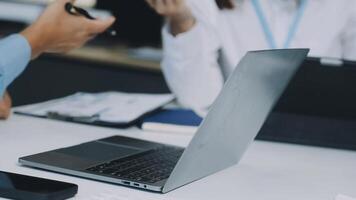 A laptop computer is sitting on a table with two people video