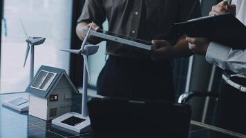 Two people are looking at a laptop with a wind turbine video