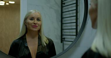 girl stands in a bathroom wearing headphones and smiling at her reflection in the mirror. She dances joyfully enjoying her time and embracing the music video