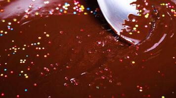 Spoon stirring chocolate with colorful sprinkles video