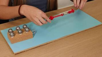 A person uses a spring scale to measure frictional force on a weighted block sliding over a surface video