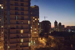 Urban skyline at dusk featuring modern high-rise buildings illuminated by warm lights, with a serene atmosphere and a hint of twilight in the background showcasing city life photo