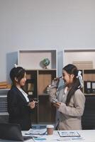 Two women in business attire sitting at a desk photo