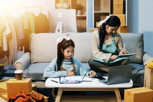 A woman and a girl sitting on a couch with a laptop photo