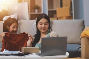 A woman and her daughter are looking at a laptop photo