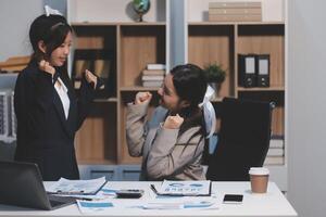 Two women in business attire are having a conversation at a desk photo