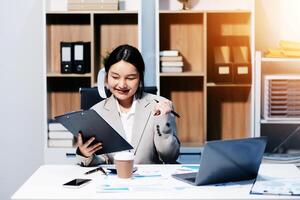Asian businesswoman working in office with laptop and papers photo