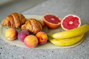 A plate of fruit and croissants on a counter photo