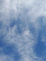 Light blue sky with soft, scattered cirrus clouds creating a wispy and textured appearance across the sky. photo