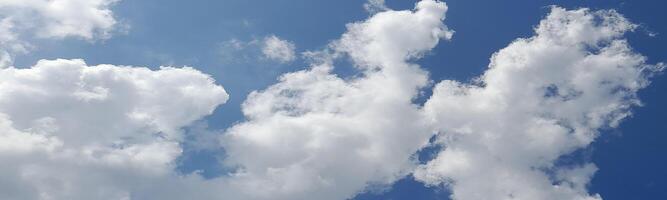 Bright blue sky with fluffy white clouds scattered across, creating a peaceful and sunny daytime atmosphere. photo