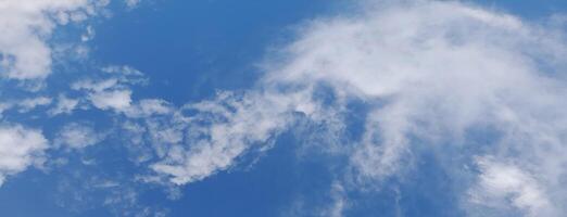 Bright blue sky with soft, wispy white clouds scattered across, creating a peaceful and airy atmosphere. photo
