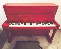 Front View of Red Upright Piano on Marble Floor photo