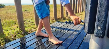 Boy, toddler a washes his feet from sand under the shower on the beach of Portugal close-up. Concept of summer, beach vacation with a child photo