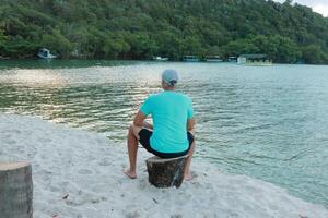 Man sitting on a stump looking out over the river photo