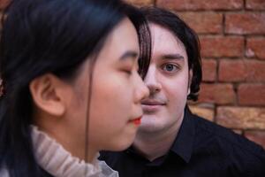 Portrait of caucasian boy with half face covered by an asian girl, concept of multiculturalism and union. photo