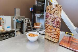A bowl of almonds next to a plastic bag during the process of packaging photo