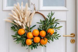 Decorative christmas wreath with oranges and bunny tails hanging on white door photo