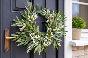 Beautiful olive branch wreath with snowberries hanging on a gray front door photo