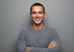 Portrait of a smiling young man with arms crossed over gray background photo