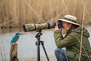 A man with a camera and a bird on a tripod photo