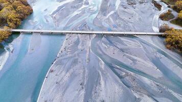 Drone footage captures a serene river and bridge in Glenorchy, New Zealand, showcasing vibrant autumn colors and winding waterways video