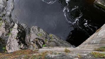 Water flows between rocks and a stone wall video