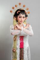 A Indonesian bride in Solo Putri attire, wearing an ornate headdress and lace kebaya. She crosses her arms in an X gesture with a determined expression, exuding strength and elegance photo