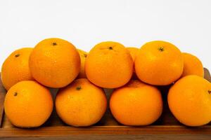 A oranges neatly stacked on a wooden tray, highlighting their freshness and bright color. photo