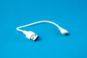 A short white USB to micro-USB cable on a blue background. Ideal for charging and data transfer for smartphones, tablets, and electronic devices. Compact and portable for everyday use. photo