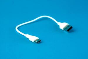 A short white USB to microUSB cable on a blue background. Ideal for charging and data transfer for smartphones, tablets, and electronic devices. Compact and portable for everyday use. photo
