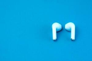 A pair of modern wireless earbuds on a vibrant blue background. Stylish and compact Bluetooth earphones designed for high-quality audio, seamless connectivity, and everyday convenience. photo
