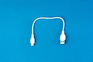 Short white USB to micro-USB cable on a blue background. Ideal for charging and data transfer for smartphones, tablets, and electronic devices. Compact and portable for everyday use. photo