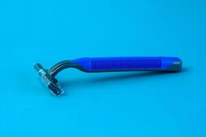 Blue disposable razor with a protective cap placed on a bright blue background. The ergonomic handle and sharp blade make it ideal for shaving facial or body hair safely and smoothly photo