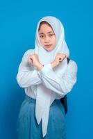 Muslim student wearing school uniform and hijab making crossed arms gesture with serious facial expression. Back to school concept with educational and disciplinary theme. photo
