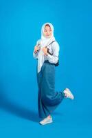 Asian Muslim teenage girl student smiling confidently while carrying backpack and holding pencil, ready to study and learn, education and back to school concept. photo