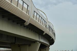 The modern elevated railway structure beautifully contrasts against a dramatic cloudy sky above photo