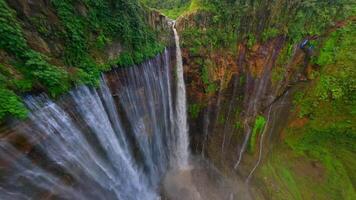 Cinematic FPV drone shot diving through the stunning multi-stream Tumpak Sewu waterfall, surrounded by lush rainforest cliffs in East Java, Indonesia. video