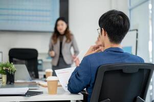 Back view of businessman or office worker holding document and look at female coworker in a meeting photo