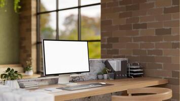 The white screen computer on marble laminate wooden working desk in an office with brick wall. photo