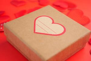 Gift box with heart design on a vibrant red background photo