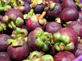 A bountiful display of deep purple mangosteen fruits with fresh green calyxes photo
