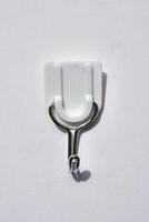 Adhesive wall hook for clothes or towel isolated on vertical white background from top angle view. photo