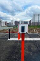 Modern urban landscape featuring a sleek black device for security parking system , with a blurred city skyline and cloudy sky in the background, showcasing contemporary infrastructure photo