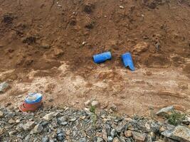 Blue drainage pipes and construction materials are scattered on dry, cracked earth, surrounded by rocky terrain, illustrating a construction site in a rural area with natural elements photo