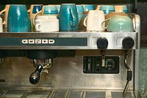 A working, well used coffee machine with different cups in a cafe photo