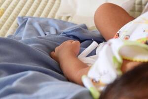Infant hands from Indonesia on white bedding photo