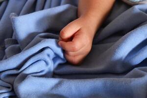 Tiny baby hand on soft fabric photo