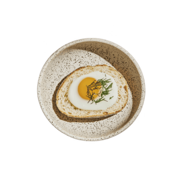 Fried egg with herbs on toast is served in speckled ceramic bowl, creating simple yet elegant breakfast presentation. dish combines rustic charm with modern touch png